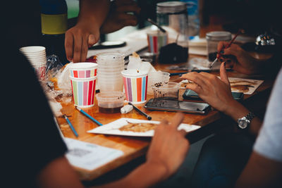 Cropped image of people enjoying food and drink on table in cafe