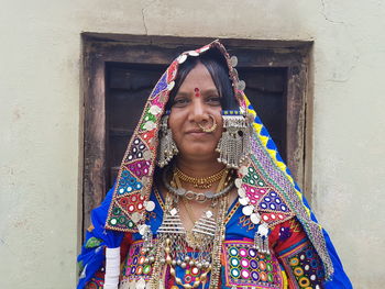 Portrait of woman in traditional clothing standing against wall