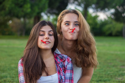 Portrait of young women eating candies on field