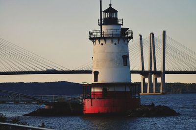 Lighthouse by sea against clear sky