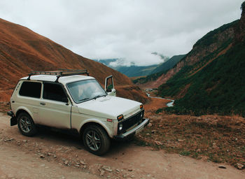 Car on road by mountains against sky