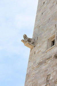 Low angle view of bird on wall against sky