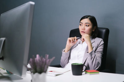 Young woman using mobile phone while sitting on table