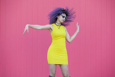 Beautiful woman standing against yellow wall