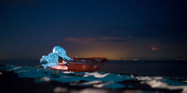 Boat moored on sea against sky at night