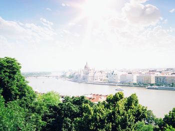 Hungarian parliament building by danube river in city against sky