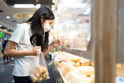 Woman holding ice cream standing at store