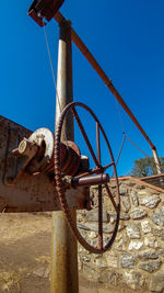 Close-up of rusty wheel against clear blue sky