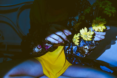 High angle view of woman holding yellow flowering plant