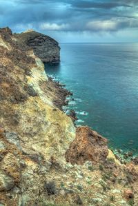 Rock formation by sea against sky