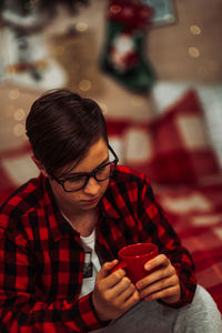 Boy holding coffee cup sitting outdoors