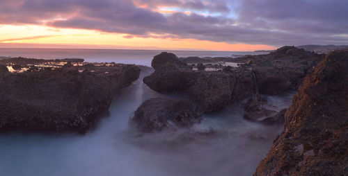 Scenic view of sea against cloudy sky during sunset