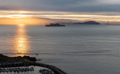 Scenic view of sea against cloudy sky during sunset