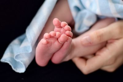 Close-up of baby feet against black background