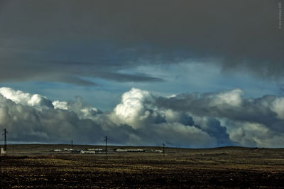 Scenic view of grassy field against cloudy sky