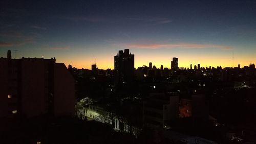 Silhouette buildings in city against sky during sunset