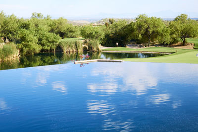 Swimming pool by lake against sky