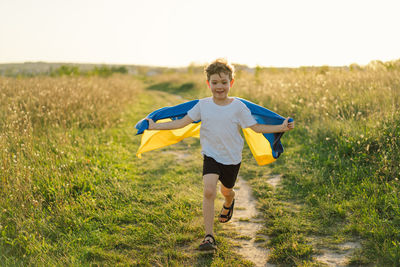 Ukrainian child boy in white t shirt with yellow and blue flag of ukraine in field.