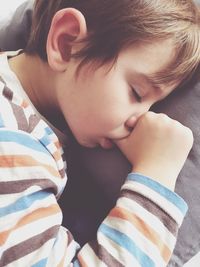 Close-up of sleeping boy sucking thumb while lying on bed