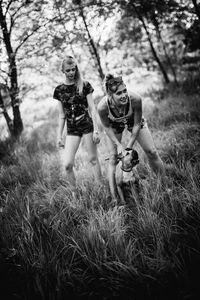 Friends playing with dog on grassy field at park