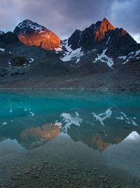 Scenic view of lake by snowcapped mountains against sky