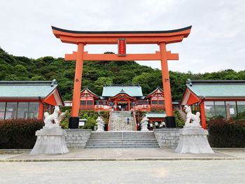 Steps under torii gate leading towards temple against sky