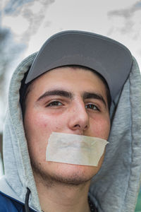 Close-up portrait of young man with adhesive tape on mouth