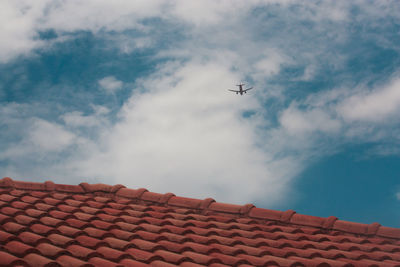 Low angle view of airplane flying over building against sky