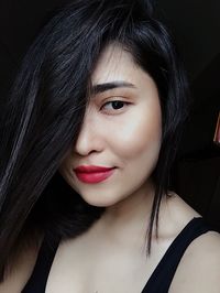 Close-up portrait of smiling young woman against black background