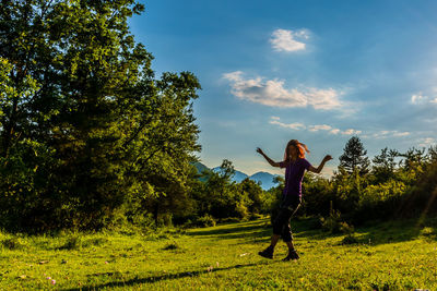 Rear view of person standing on field against sky