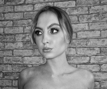 Portrait of woman against brick wall