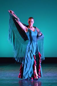 Portrait of young woman dancing on stage against wall