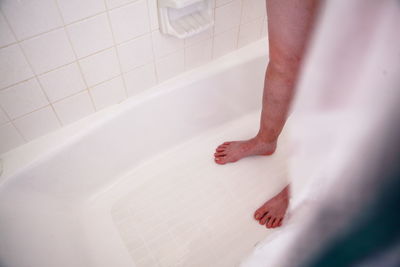 Low section of person standing in bathtub