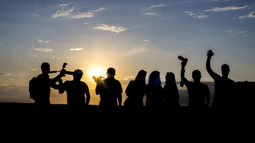 Silhouette people standing against sky during sunset