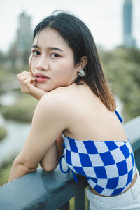 Portrait of young woman looking away while standing outdoors