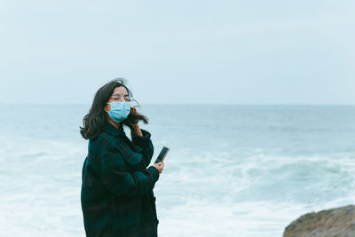 Young woman looking at sea against clear sky