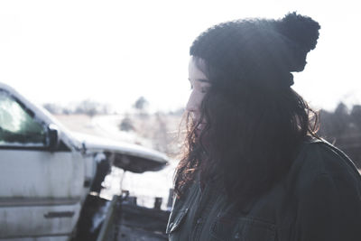 Close-up of woman wearing knit hat while standing against clear sky