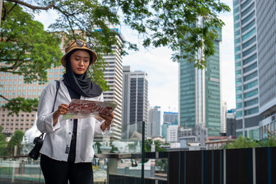 Full length of teenage girl standing against buildings in city