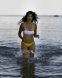 Full length of young woman in sea against sky