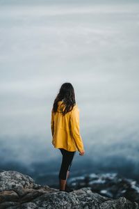 Rear view of woman standing on rock