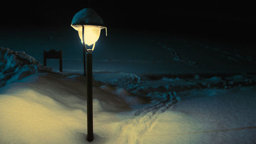 Close-up of illuminated lamp on street light at night