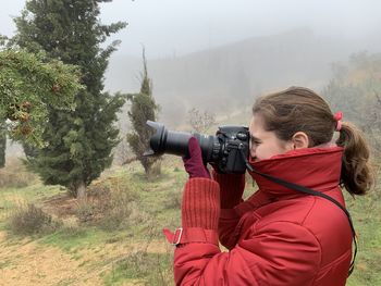 Side view of girl photographing in foggy weather