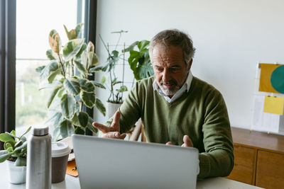 Mature man doing video call on laptop while sitting at home