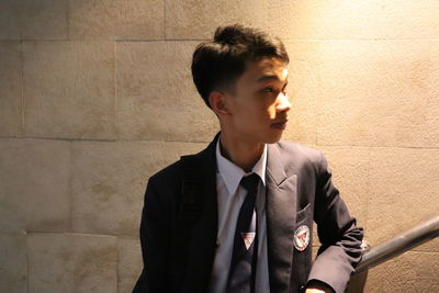 Young man looking away against wall