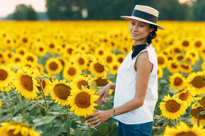 Portrait of young woman standing amidst yellow flowers