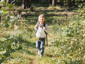 Curious boy is hiking in forest. child with binoculars and backpack. summer journey. adventure time.