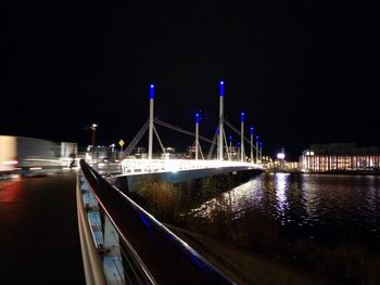 Road passing through illuminated bridge at night