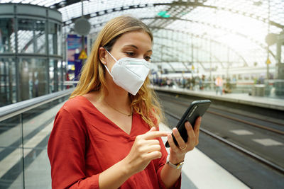 Close-up of woman with protective face mask using smartphone in berlin train station, germany