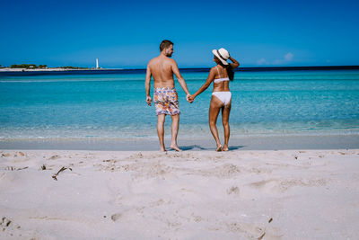 Full length of men standing on beach against sea