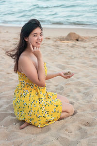 Portrait of young woman sitting at beach